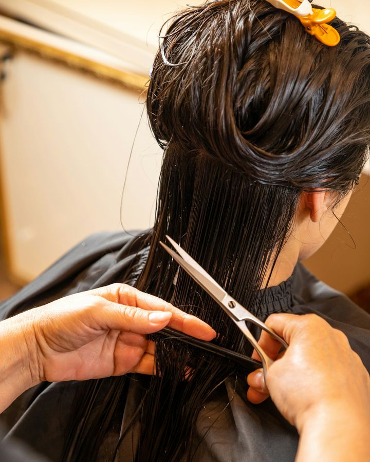 Coiffeuse coupant aux ciseaux des cheveux mouillés